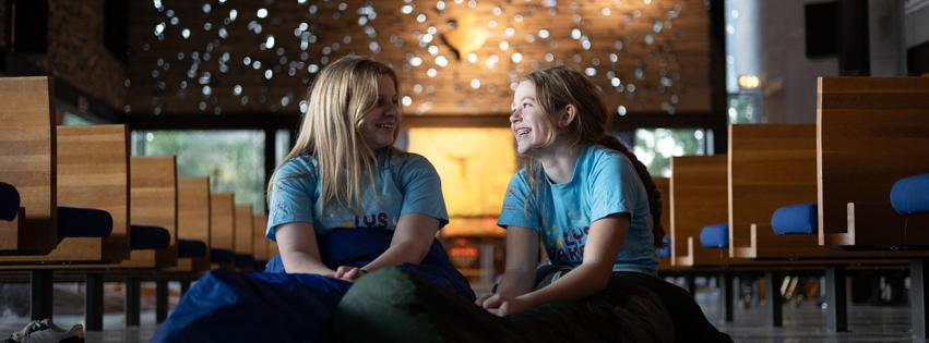 To barn sitter med soveposer i et kirkerom